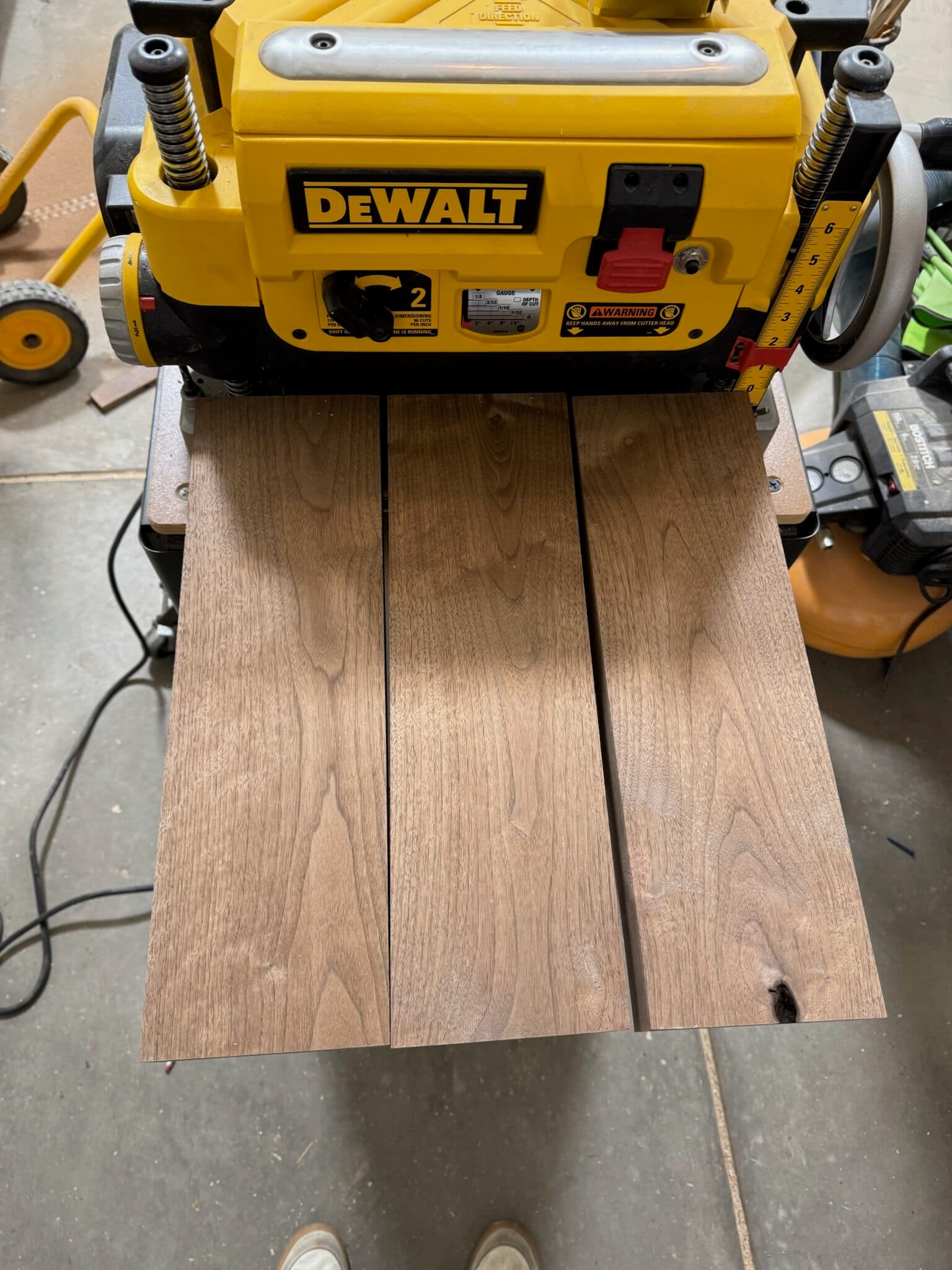 Walnut boards beneath a thickness planer