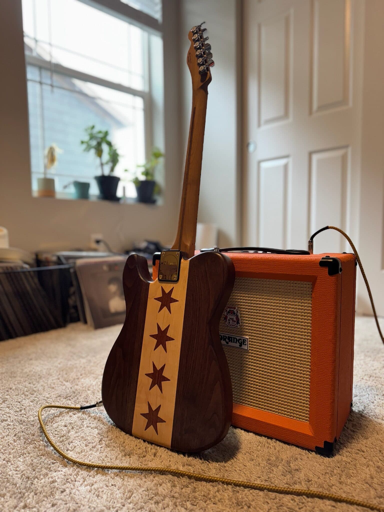 Completed walnut Chicago Telecaster beside a small amplifier